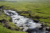 Vágar island, Faroes: hiker crossing a stream on the moorlands - photo by A.Ferrari